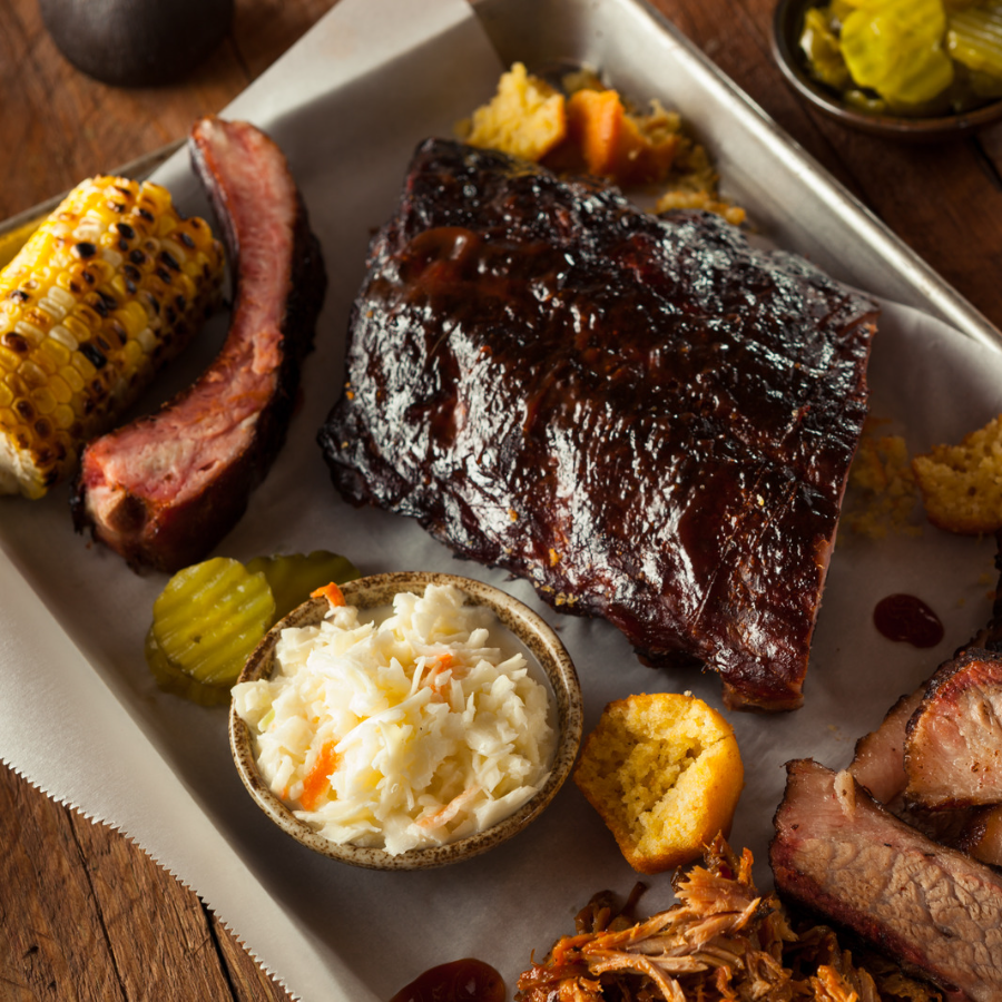 picnic barbeque dinner plate with grilled pork ribs, corn on the cob, coleslaw and other food