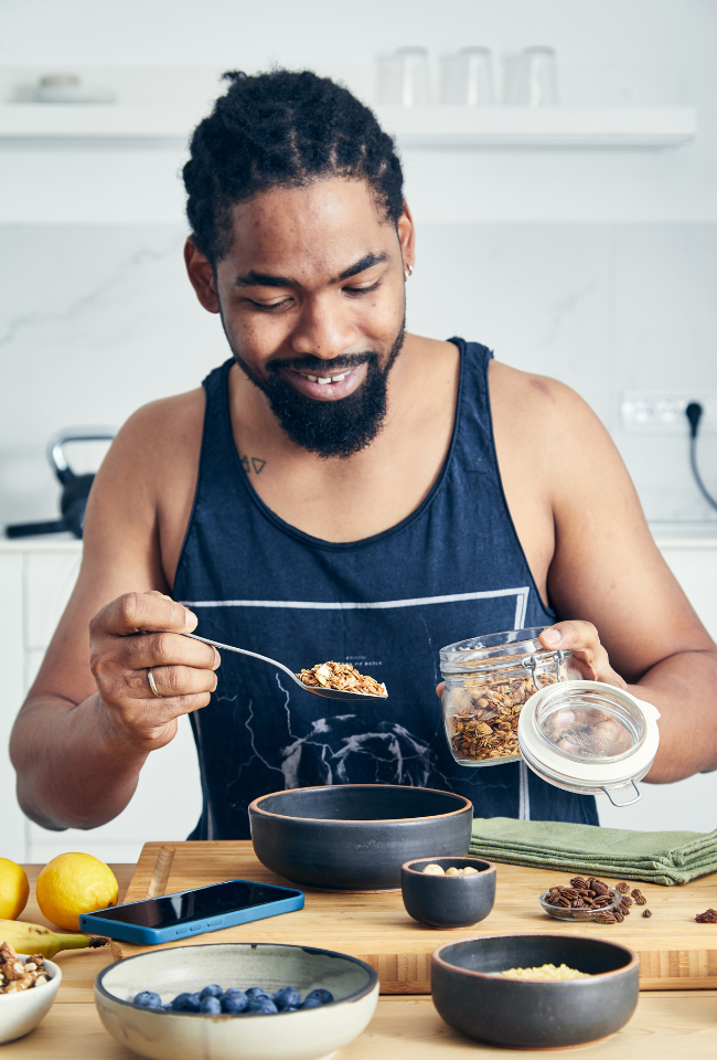 man in sports wear eating granola, blueberries, pecans.